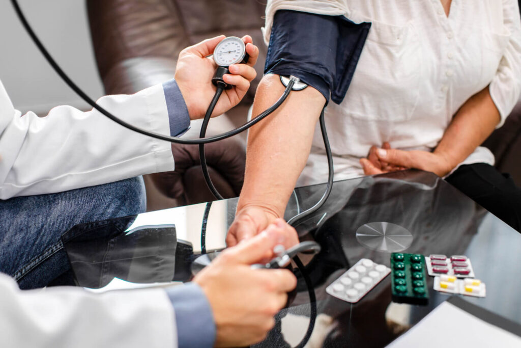 Medico misura la pressione arteriosa a una paziente con sfigmomanometro durante una visita di controllo.