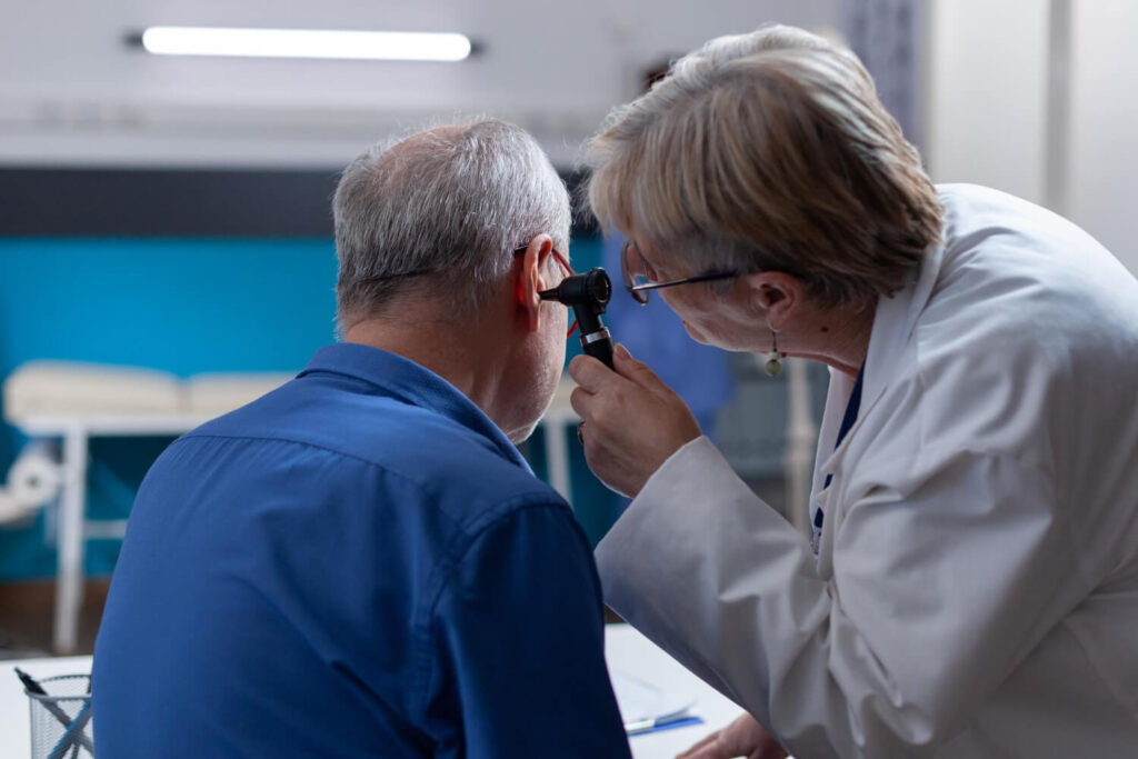 Un medico esegue un controllo dell'udito con l'apposito strumento ad un uomo anziano in uno studio medico.