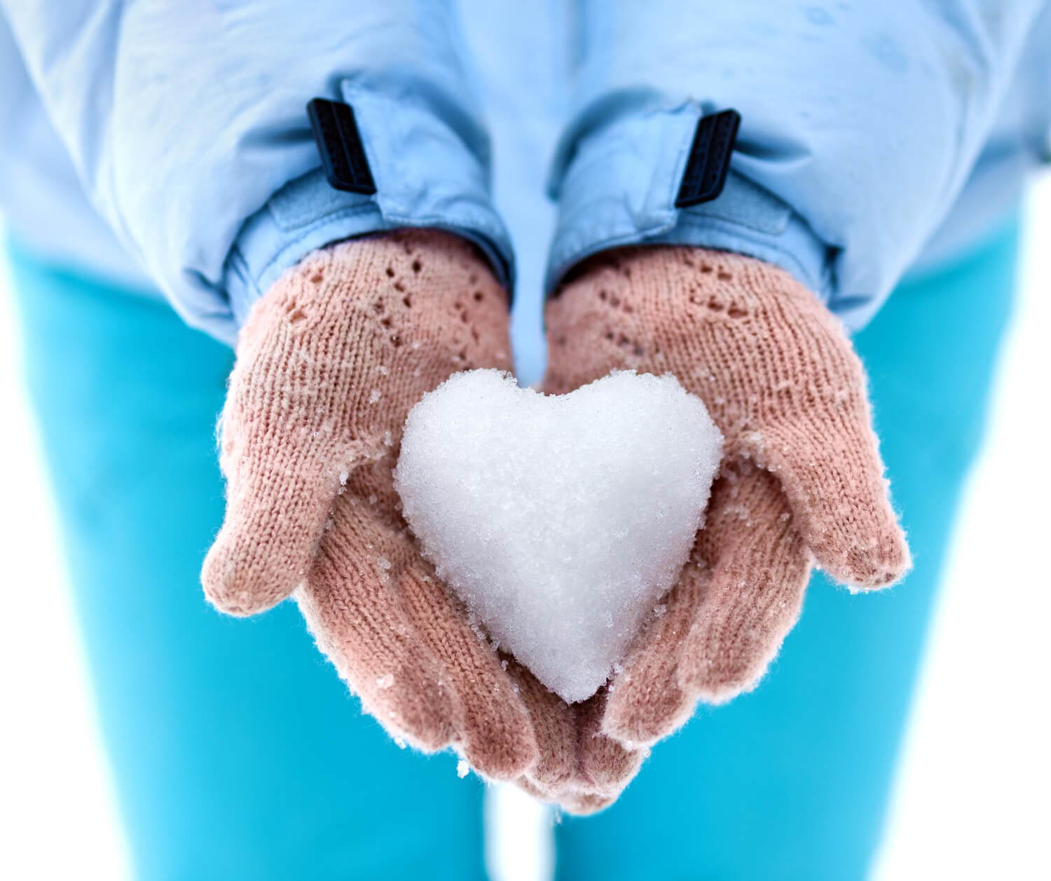 Donna tiene tra le mani un cuore stilizzato fatto di neve, simbolo di prevenzione della salute nei mesi freddi.